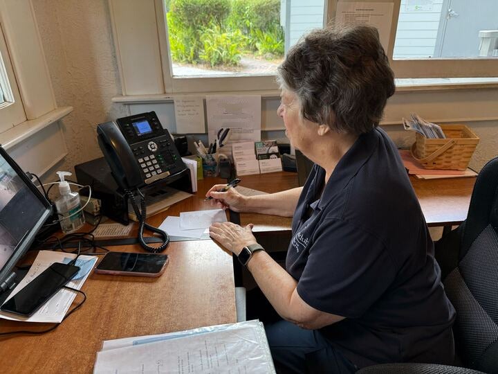 A woman answers a phone at a desk.